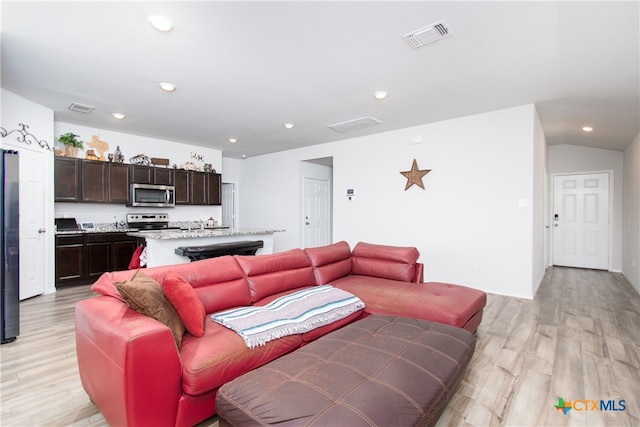 living room featuring light wood-type flooring and vaulted ceiling