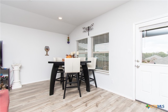 dining space featuring light wood-type flooring, lofted ceiling, and a healthy amount of sunlight