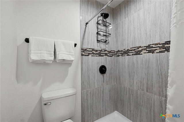 bathroom featuring tiled shower and toilet