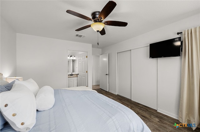 bedroom with connected bathroom, dark wood-type flooring, a closet, and ceiling fan