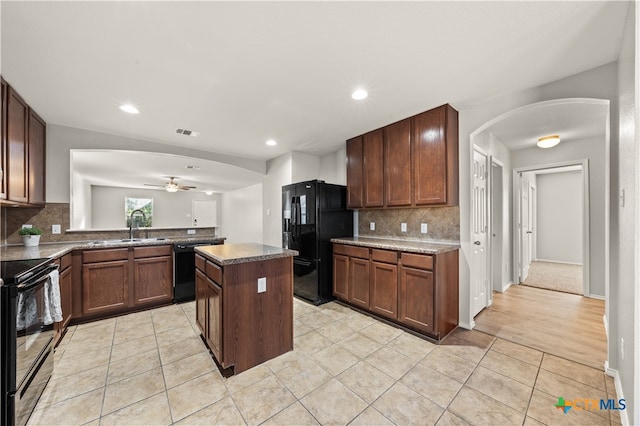 kitchen featuring black appliances, decorative backsplash, a center island, and light tile patterned floors