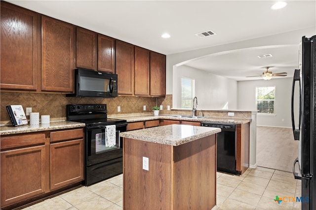 kitchen featuring sink, a center island, light tile patterned flooring, and black appliances