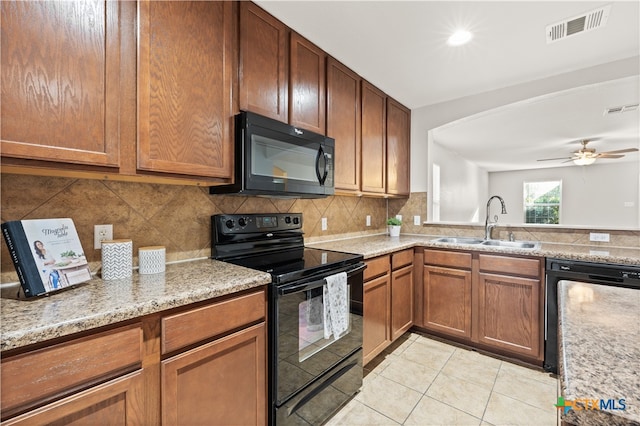 kitchen featuring light stone countertops, sink, decorative backsplash, light tile patterned flooring, and black appliances