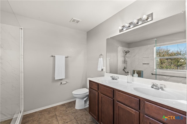 bathroom featuring tile patterned floors, vanity, a tile shower, and toilet