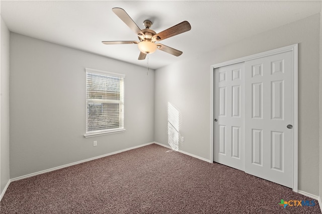 unfurnished bedroom with ceiling fan, a closet, and dark carpet