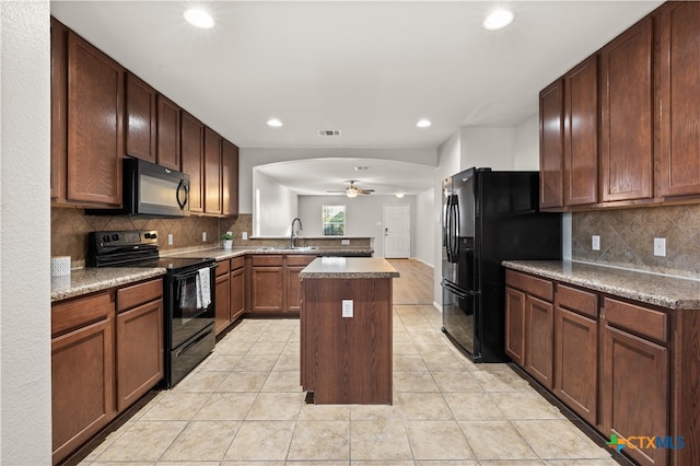 kitchen featuring kitchen peninsula, tasteful backsplash, sink, black appliances, and a kitchen island