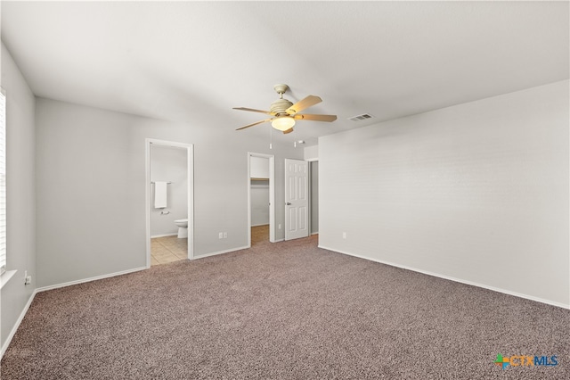 unfurnished bedroom featuring ensuite bathroom, ceiling fan, a spacious closet, and light colored carpet