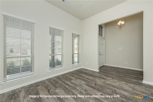 spare room with dark wood-type flooring and a chandelier