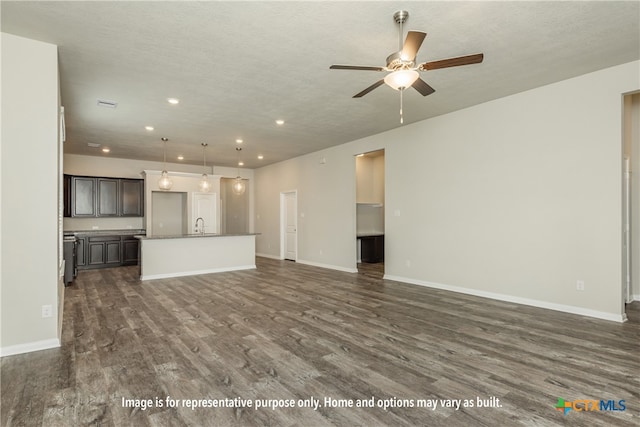 unfurnished living room featuring ceiling fan, dark hardwood / wood-style floors, and a textured ceiling