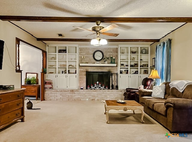 carpeted living room with a brick fireplace, ceiling fan, beam ceiling, and a textured ceiling