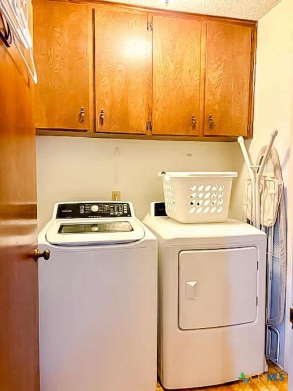 clothes washing area featuring cabinets and separate washer and dryer