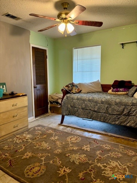 bedroom with ceiling fan and a textured ceiling