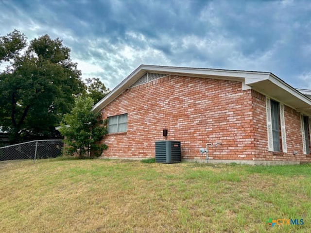 view of side of property with central AC unit and a yard