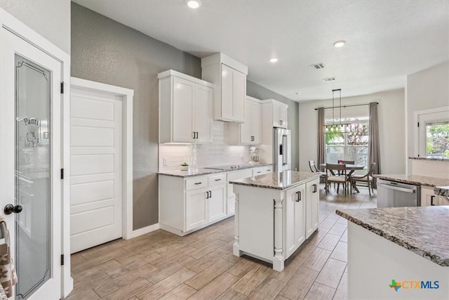 100 Metheglin Dr, Temple, TX 76502 - kitchen with appliances with stainless steel finishes, white cabinetry, a center island, light wood-style floors, and light stone counters