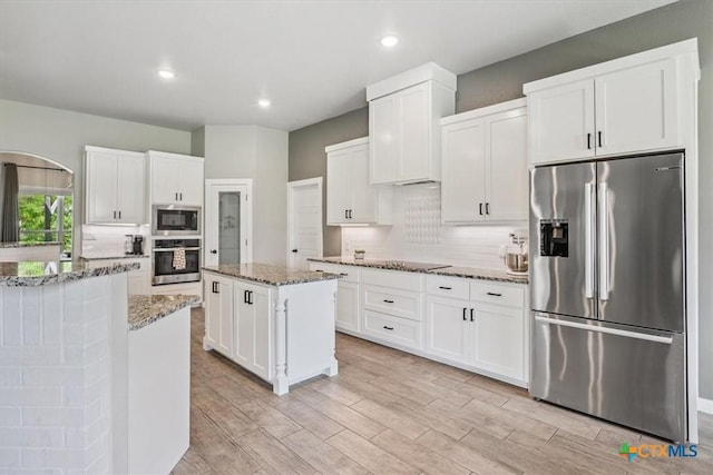 100 Metheglin Dr, Temple, TX 76502 - kitchen with stainless steel appliances, a center island, white cabinetry, backsplash, and light stone counters