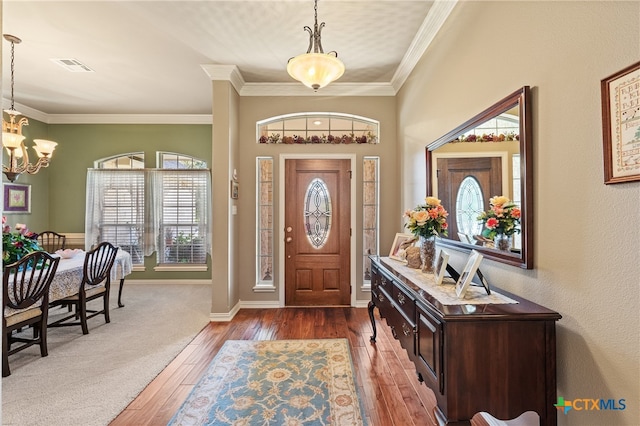 entryway featuring dark hardwood / wood-style floors, crown molding, and a notable chandelier