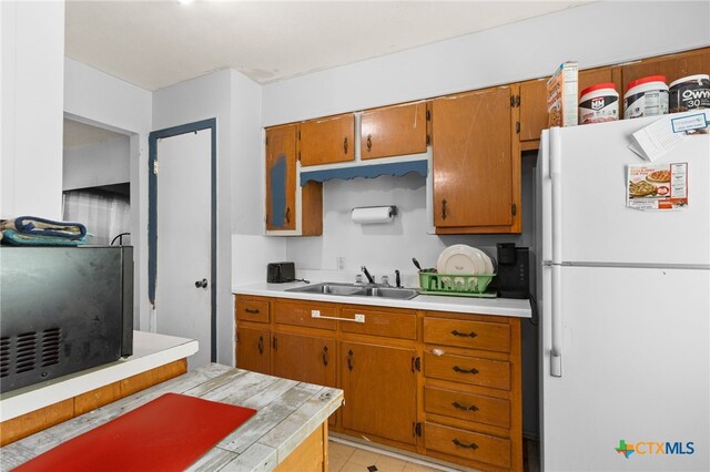 603 S 13th St, Copperas Cove, TX 76522 - kitchen featuring freestanding refrigerator, light countertops, brown cabinets, and light tile patterned floors