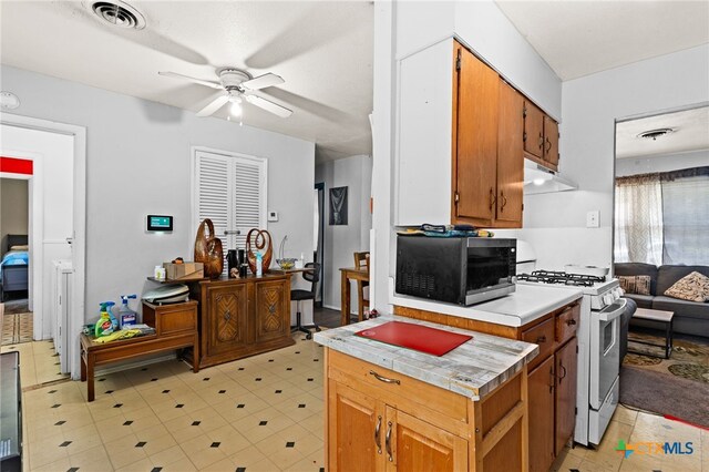 603 S 13th St, Copperas Cove, TX 76522 - kitchen with gas range gas stove, a ceiling fan, light countertops, under cabinet range hood, and brown cabinets