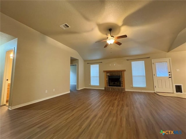 unfurnished living room featuring vaulted ceiling, ceiling fan, a textured ceiling, a fireplace, and dark hardwood / wood-style flooring