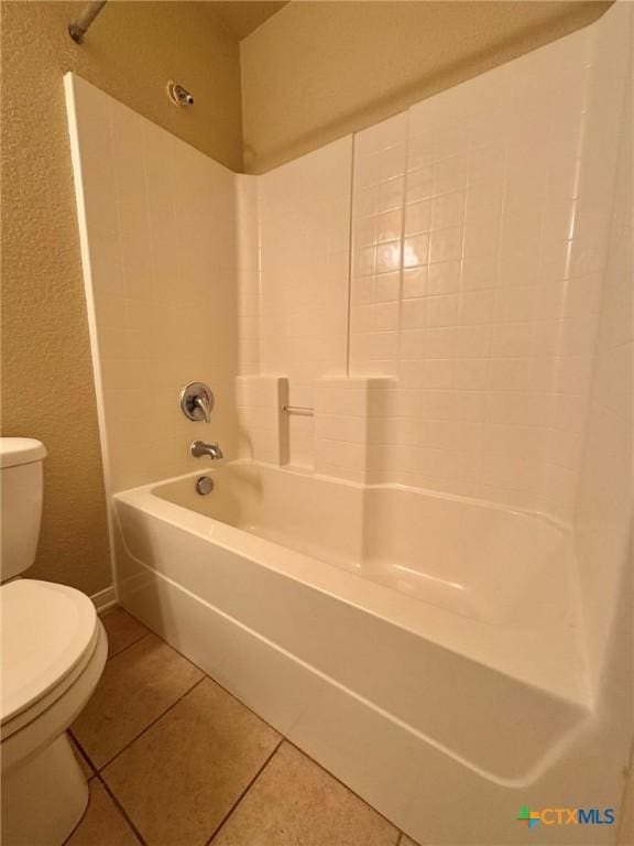 bathroom featuring tile patterned floors, toilet, and washtub / shower combination