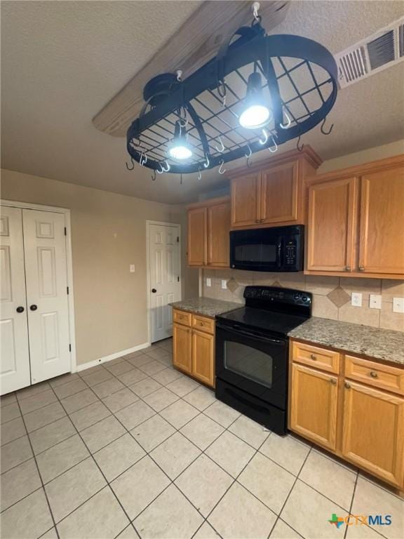 kitchen with light tile patterned floors, light stone counters, ceiling fan, and black appliances