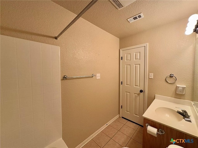 bathroom featuring a shower, tile patterned flooring, vanity, and a textured ceiling