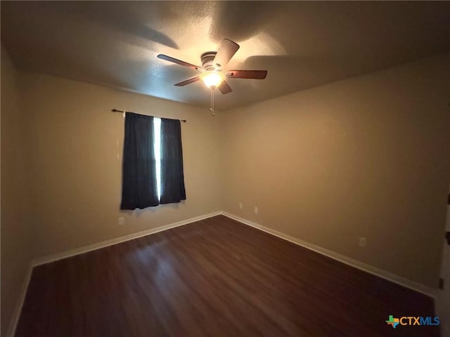 spare room with a textured ceiling, ceiling fan, and dark wood-type flooring