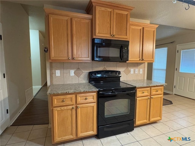 kitchen featuring tasteful backsplash, light stone counters, light tile patterned flooring, and black appliances