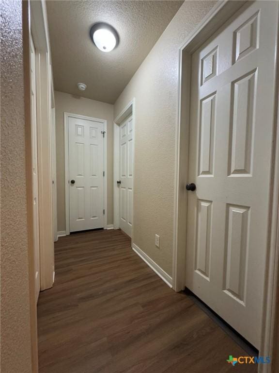 hall with dark wood-type flooring and a textured ceiling