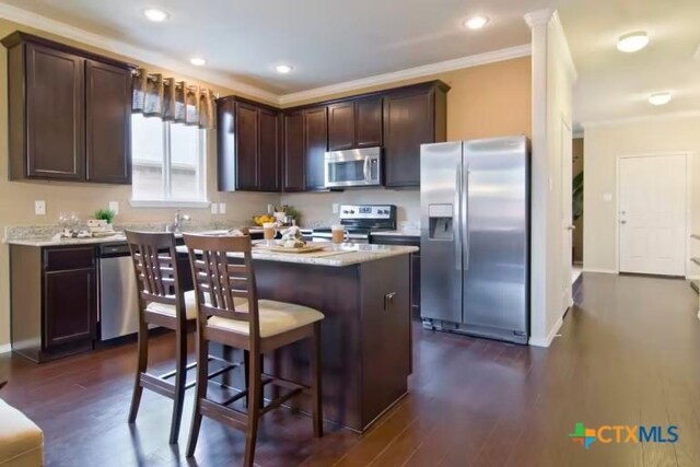 1575 Laila Ln, Belton, TX 76513 - kitchen featuring stainless steel appliances, dark brown cabinets, a center island, ornamental molding, and dark wood-style floors