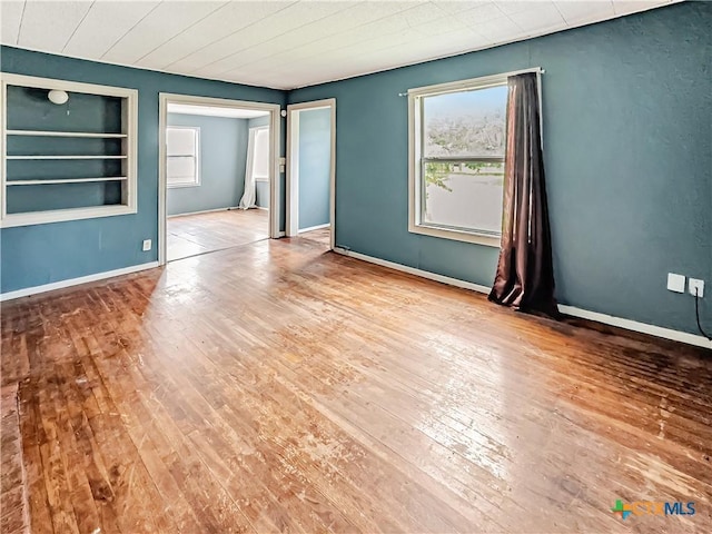 1805 E N St, Victoria, TX 77901 - empty room with healthy amount of natural light, hardwood / wood-style floors, and built in shelves
