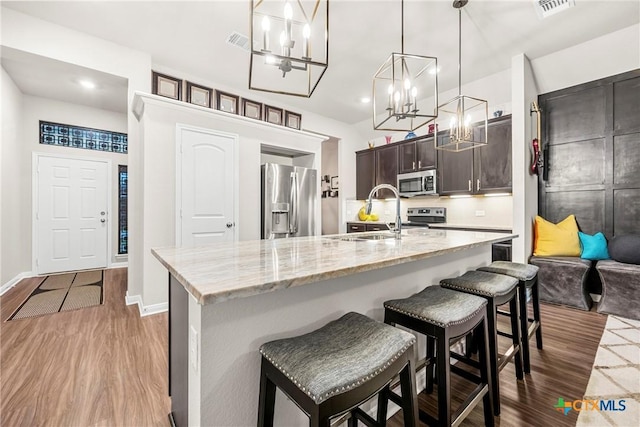 7907 Montclair Dr, Temple, TX 76502 - kitchen featuring stainless steel appliances, a chandelier, wood finished floors, a kitchen breakfast bar, and recessed lighting