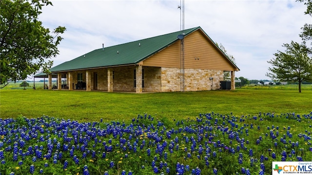 back of property featuring central AC unit and a yard