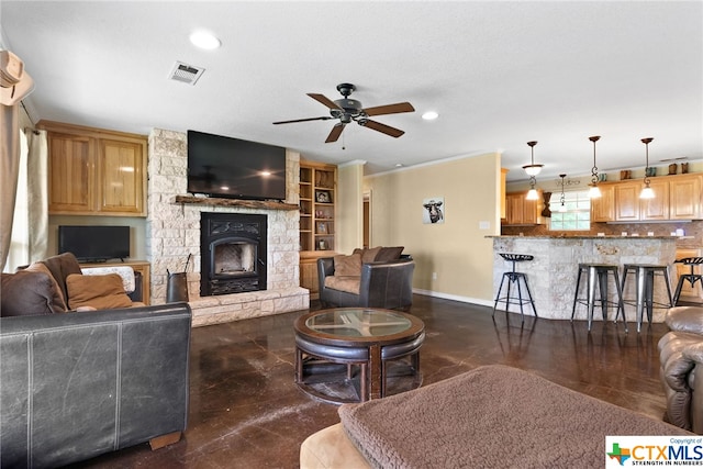 living room with a fireplace, built in features, ceiling fan, and crown molding