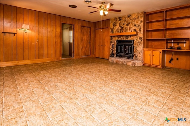 unfurnished living room with wood walls, built in features, and ceiling fan