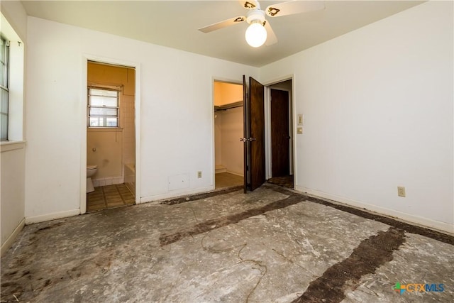 unfurnished bedroom featuring a walk in closet, a closet, ensuite bath, and ceiling fan