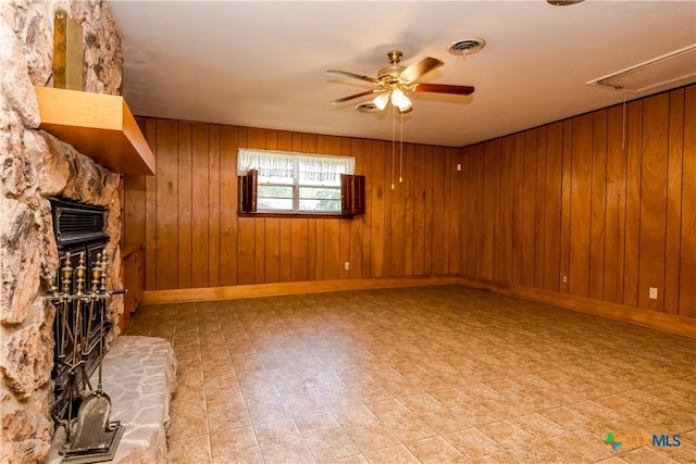 unfurnished living room featuring ceiling fan and wood walls