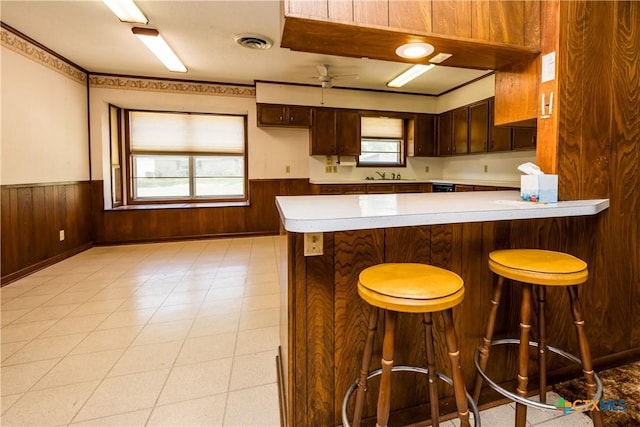 kitchen featuring a kitchen breakfast bar, kitchen peninsula, ceiling fan, and a wealth of natural light