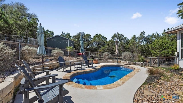 view of swimming pool with a fenced in pool, a patio, an outbuilding, and a fenced backyard