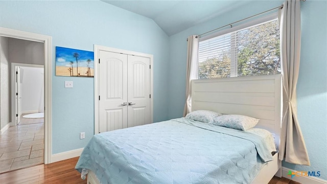 bedroom featuring vaulted ceiling, wood finished floors, a closet, and baseboards