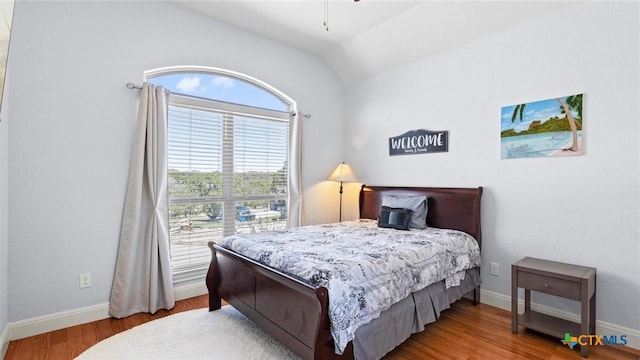 bedroom featuring baseboards, wood finished floors, and vaulted ceiling