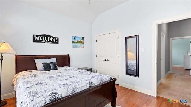 bedroom featuring lofted ceiling, wood finished floors, baseboards, and a closet