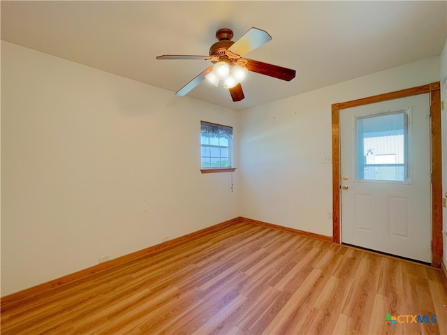 empty room with a wealth of natural light, ceiling fan, and light hardwood / wood-style flooring