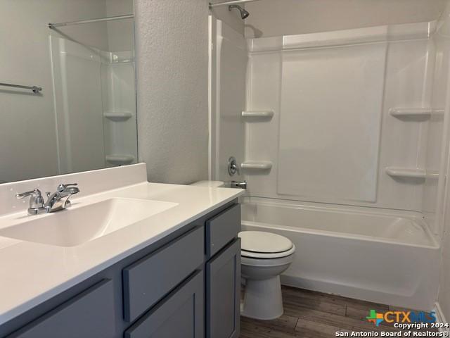 2537 Windle Ln, Seguin, TX 78155 - bathroom with vanity, toilet, wood finished floors, shower / tub combination, and a textured wall