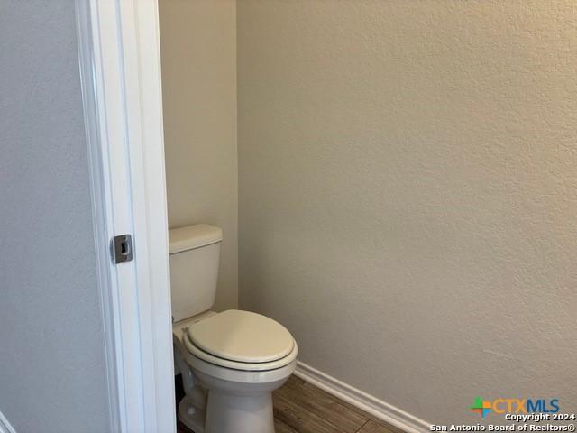 2537 Windle Ln, Seguin, TX 78155 - bathroom featuring baseboards, toilet, wood finished floors, and a textured wall