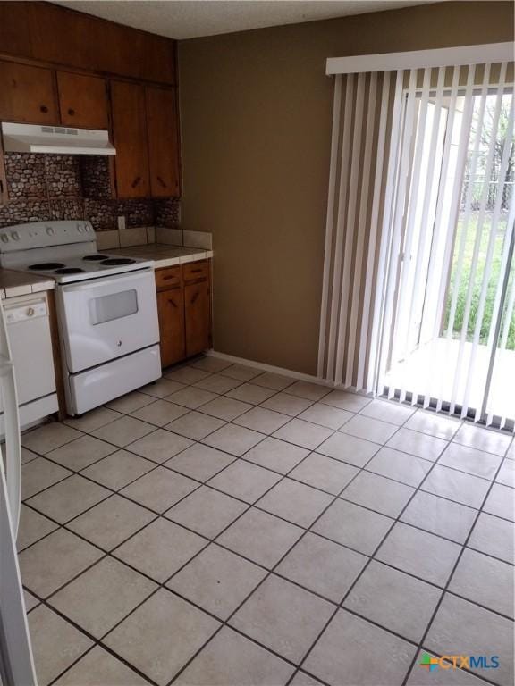 kitchen with decorative backsplash, light tile patterned floors, and white appliances