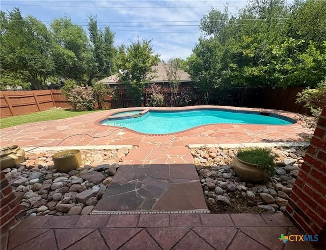 view of swimming pool featuring a fenced backyard, a patio area, and a pool with connected hot tub