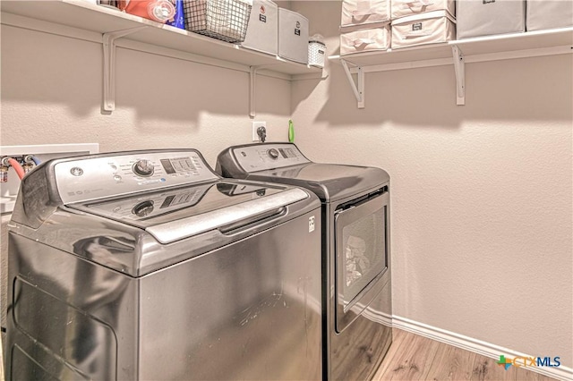 laundry area with baseboards, wood finished floors, laundry area, and washing machine and clothes dryer