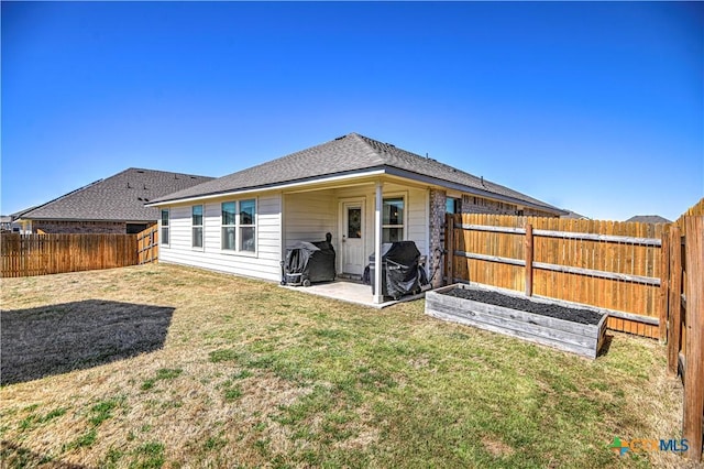 rear view of property featuring a yard, a shingled roof, a fenced backyard, and a patio area