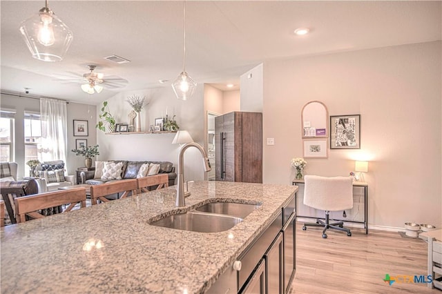 kitchen featuring decorative light fixtures, light wood-style floors, visible vents, and a sink